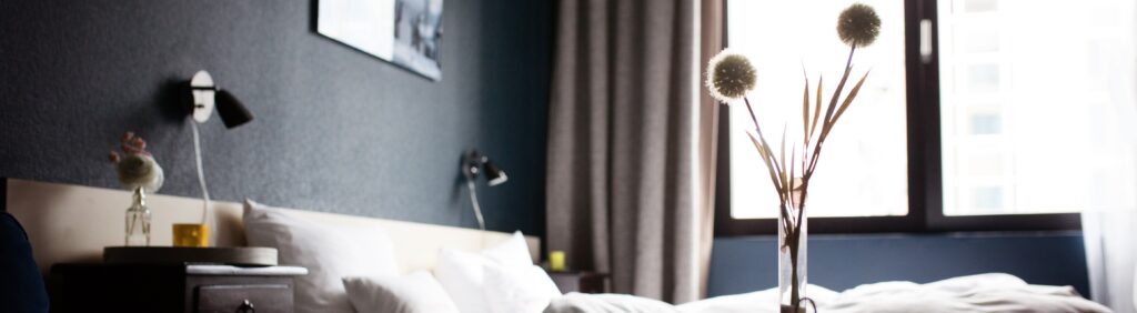 Camera di hotel: letto, finestra e vasetto decorativo in primo piano